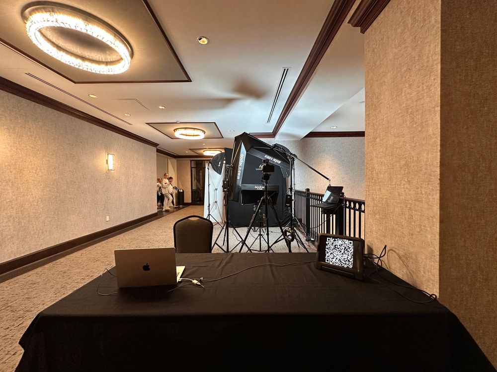 A complete headshot station with studio lights, backdrop and private delivery screen set up at an event